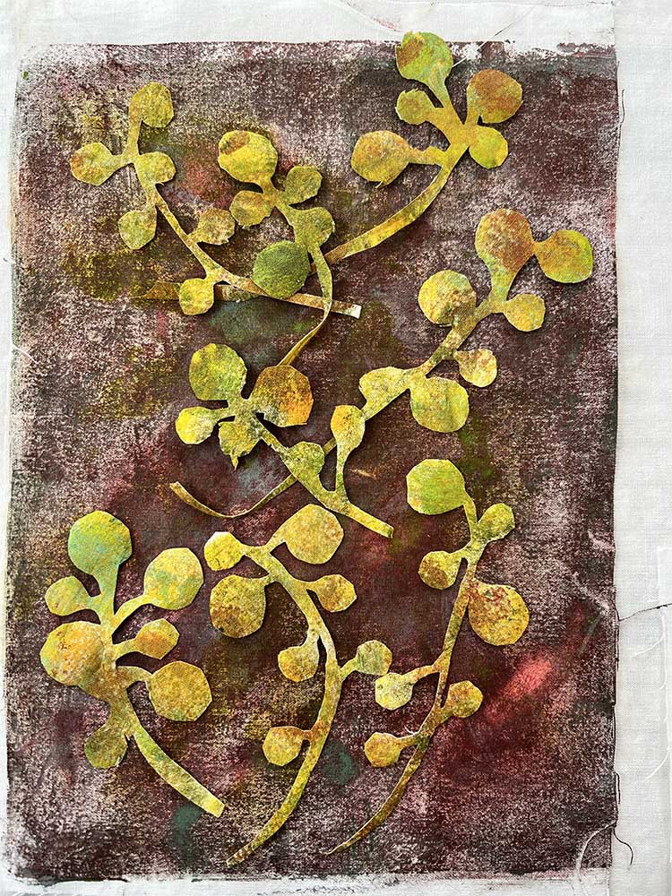 Photograph of pieces of hand cut fabric arranged on a background panel.